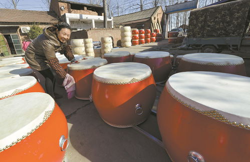 襄城县麦岭镇欧营村宏声乐器厂工作人员正在对制作好的大鼓进行最后整理
